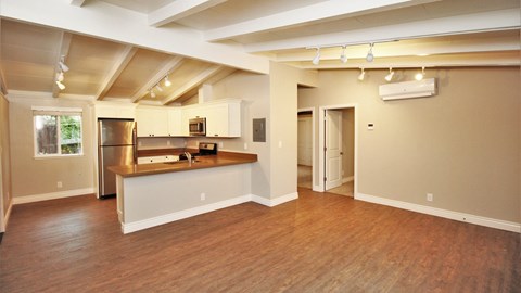an empty living room and kitchen with a wood floor